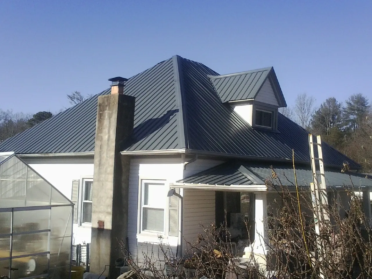 Dark blue standing seam metal roof on a white farmhouse with dormer — Slate & Tile Roof Repair by Roofing Brothers in Mount Croghan