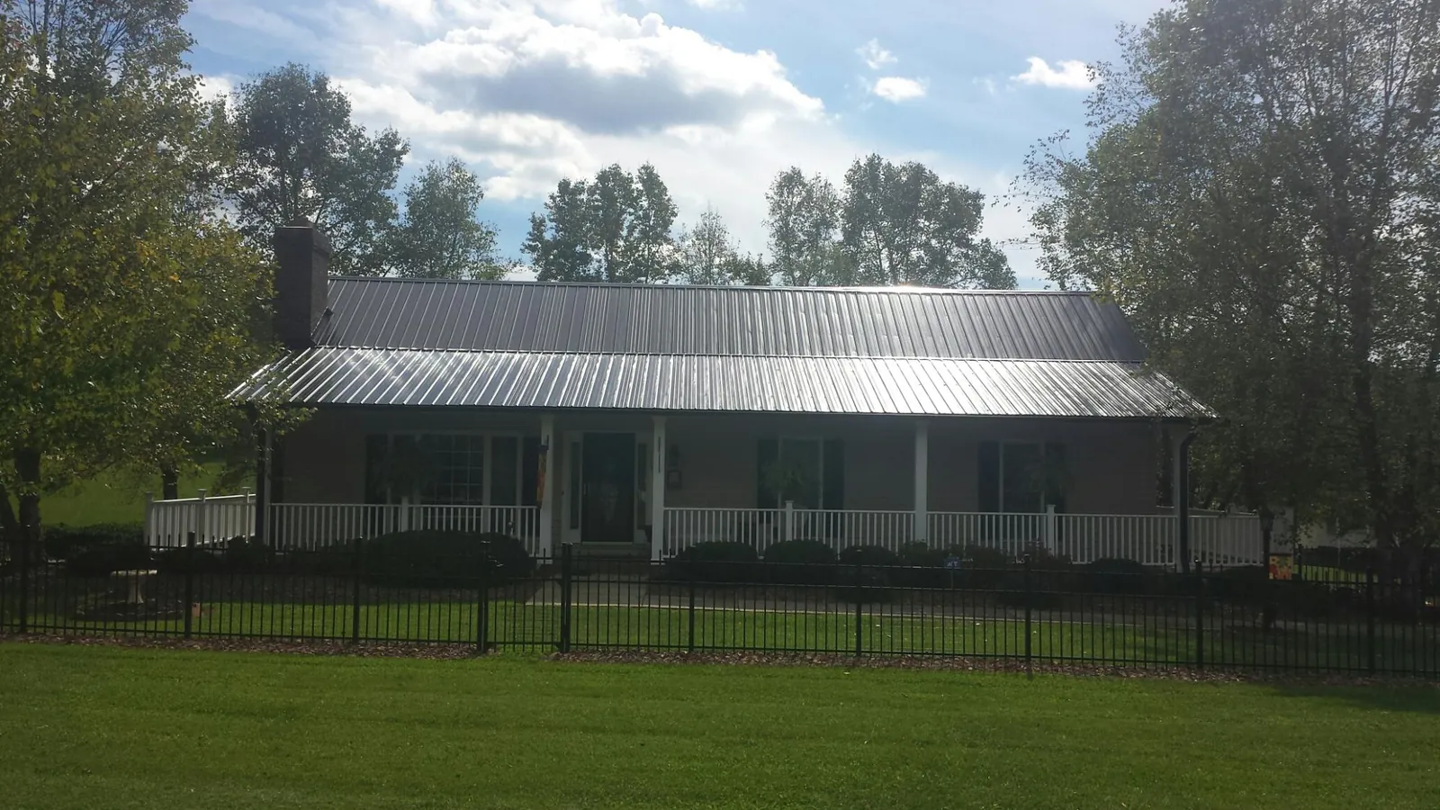 Gray metal roof on a brick ranch with a full width front porch — Gutter Guard Installation work by our crew in Mount Croghan