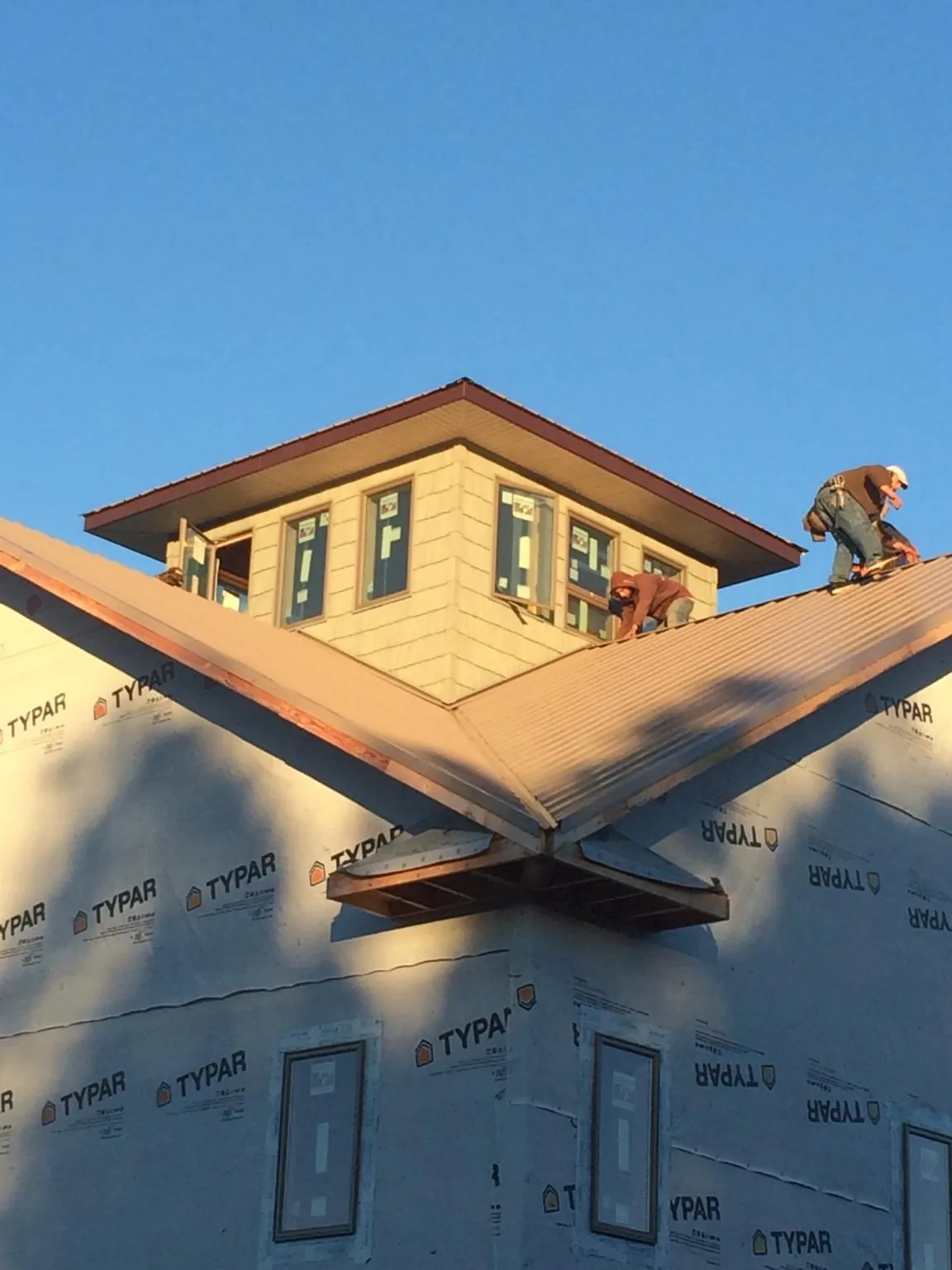 Roofers working around a rooftop cupola on a new metal roof at sunset — Roof Waterproofing in Mount Croghan by Roofing Brothers